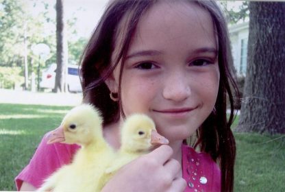 Tiffany Smith, 4th generation Smith family holding a pair of White Chinese goslings.