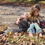 child sitting with pet turkey
