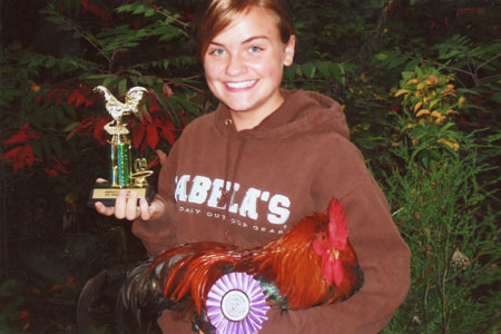 A chicken keeper holds her bird and the award she won at a local fair.