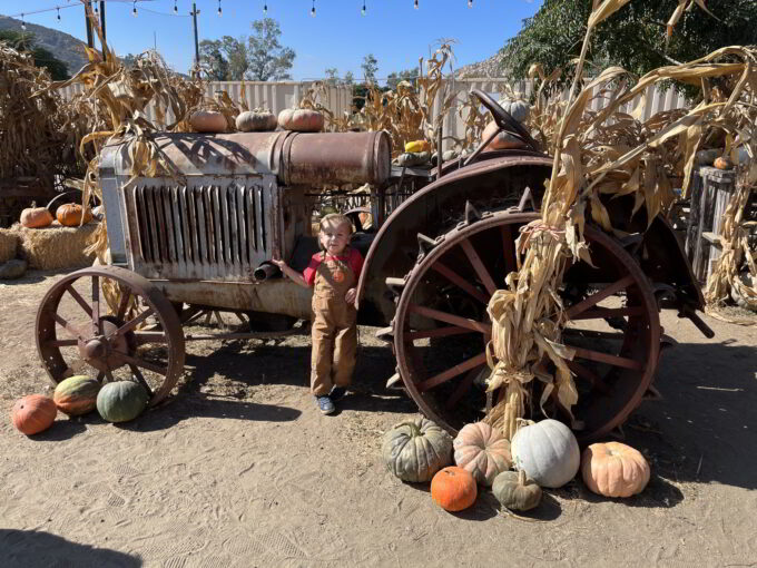 Kid in front of old rusty tractor