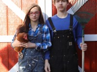 Teenagers in front of barn door holding a chicken