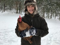 Boy holding chicken in the snow
