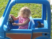 toddler taking chicken for ride in toy pedal car
