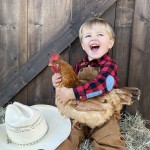 Boy with cowboy hat holding chicken