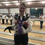 Child holding chicken with winning ribbon.