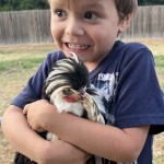 Boy holding chicken with funny face