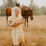 Piper Tidwell - girl holding chicken in front of horses